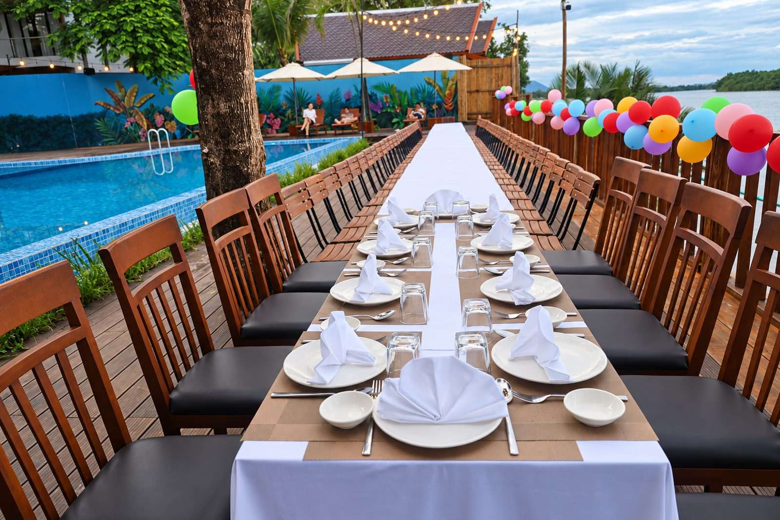 A long banquet table laid beside the pool for a group celebration